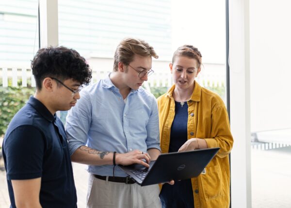 Employees gathered around a laptop at work